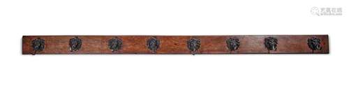 A long oak wall coat rack with eight bronze lion mask hooks