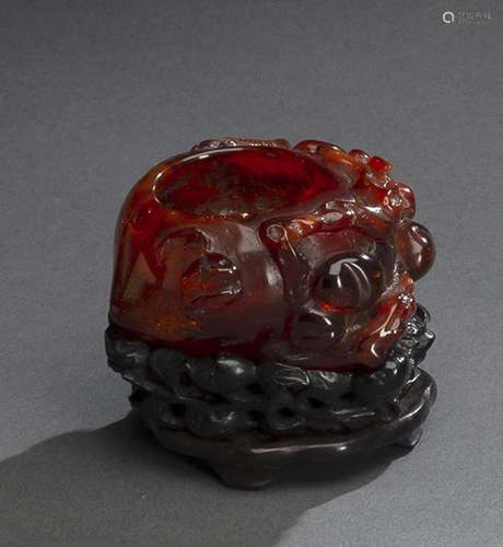 A PEACH-SHAPED CARVED AMBER BRUSHWASHER ON CARVED WOOD STAND