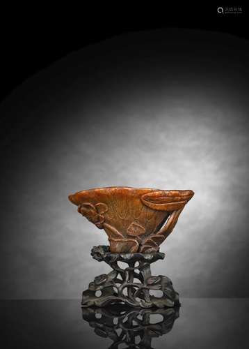 A SUPERB CARVED RHINOHORN LOTUS WINE CUP ON CARVED WOOD STAN...