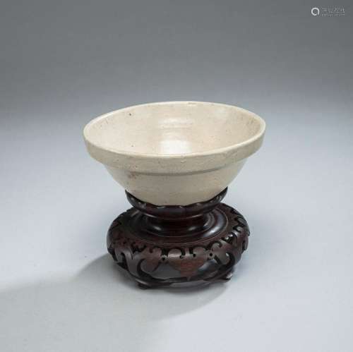 FUNNEL-SHAPED CERAMIC BOWL WITH BEIGE GLAZE ON A CARVED WOOD...
