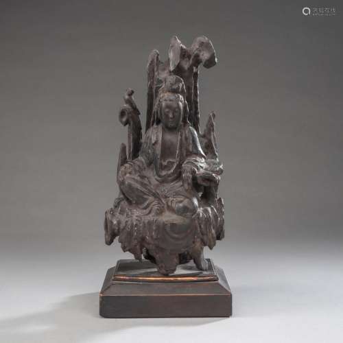 A WOOD CARVING OF GUANYIN SEATED ON A ROCK