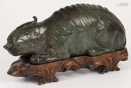 A jadeiete statuette of a mythical creature on a hardwood ba...