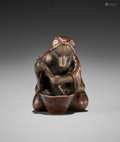 A WOOD NETSUKE OKIMONO OF A TANUKI STIRRING MISO IN A MORTAR