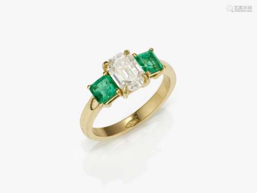 An eternity ring decorated with emeralds and a diamond in em...