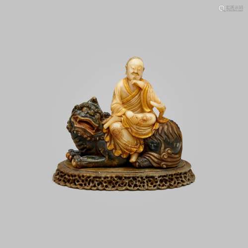 A tinted and parcel-gilt soapstone figure of an arhat seated...