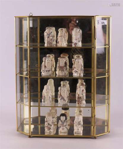 A collection of twelve bone netsukés in brass display case, ...