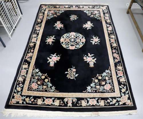 A woolen Oriental carpet with floral motifs on a black groun...