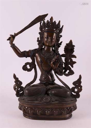 A brown patinated bronze Manjushri Bodhivisattva on lotus cr...