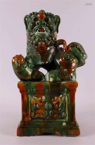 A Sancai glazed reclining Dog or Foo with paw on its young, ...