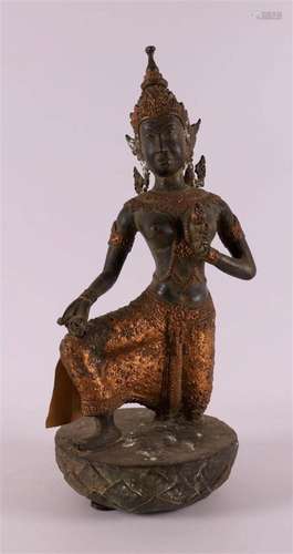 A green patinated and gilded kneeling Buddha on a lotus crow...