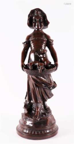 A bronzed metal sculpture of a girl with puppies in a basket...