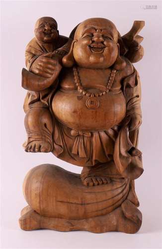 A tropical wooden sculpture of a laughing Buddha with child,...