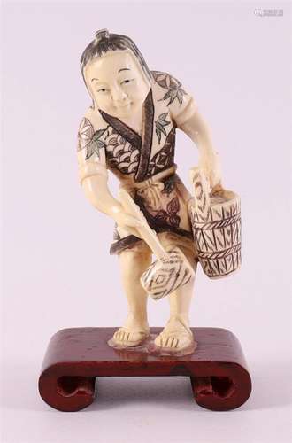 An ivory okimono of a woman with a bucket and hammer, Japan,...