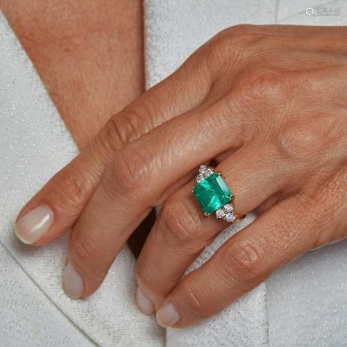An emerald and diamond ring. It is adorned with a square cut...