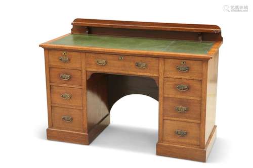 AN EDWARDIAN OAK DESK, the tooled leather-inset top with gal...