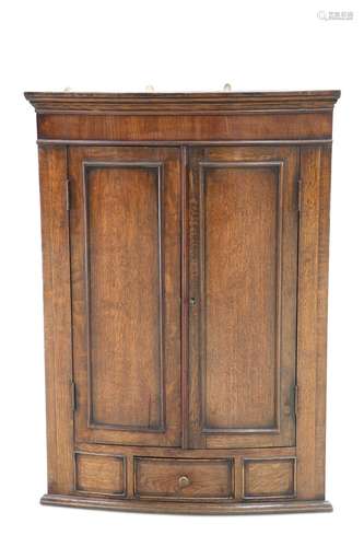 A GEORGE III-STYLE OAK BOW-FRONT HANGING CORNER CUPBOARD, fi...