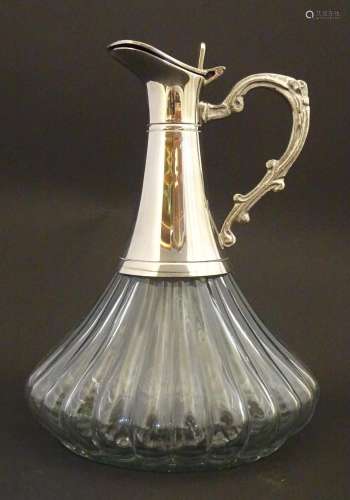 A glass claret jug with lobed decoration and silve…