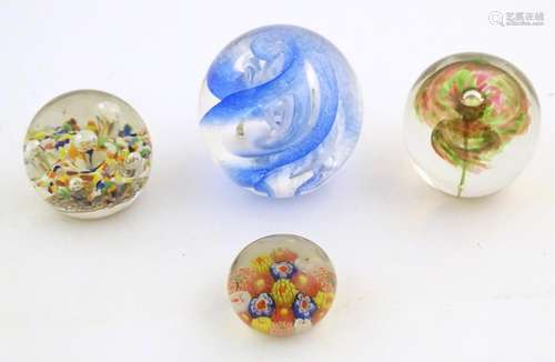 Four assorted glass paperweights. The largest appr…