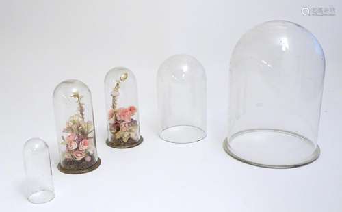 Five glass domes, to include a pair containing flo…