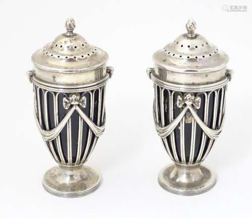 A pair of silver pepperettes of urn shape with bow…