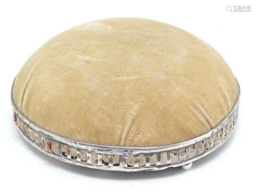 A circular, domed pin cushion with a silver base, …