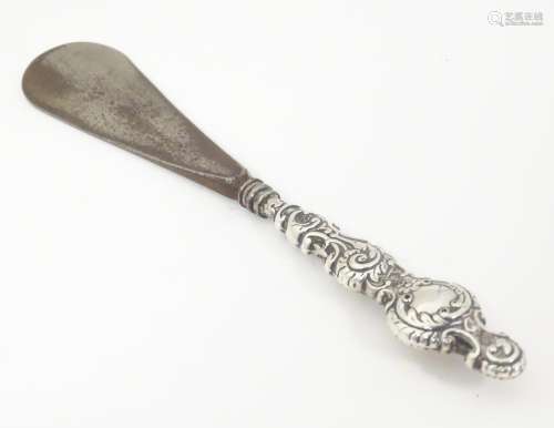 A silver handled shoe horn with embossed decoratio…