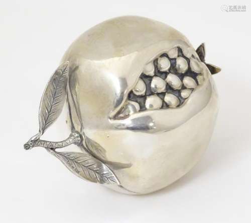 A silver miniature model of a pomegranate fruit. A…