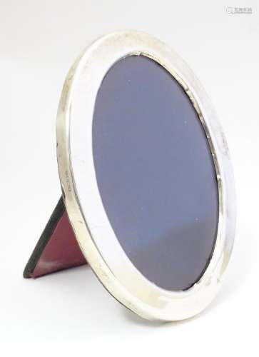 A photograph frame of oval form with silver surrou…