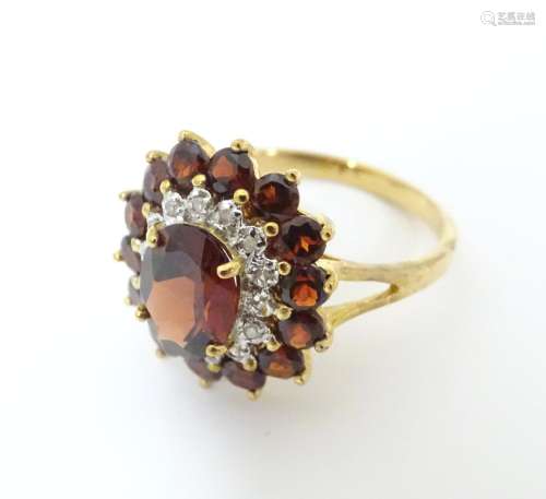 A 9ct gold ring set with central garnet bordered b…