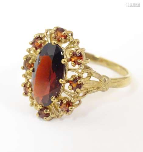 A 9ct gold ring set with a central oval garnet bor…