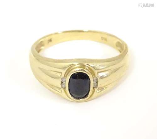 A 9ct gold ring set with central dark stone flanke…