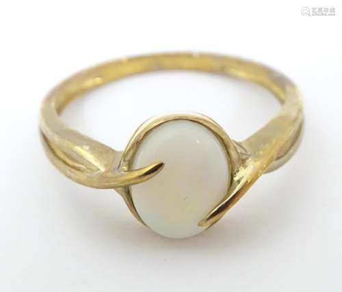 A 9ct gold ring set with central opal cabochon. Ri…