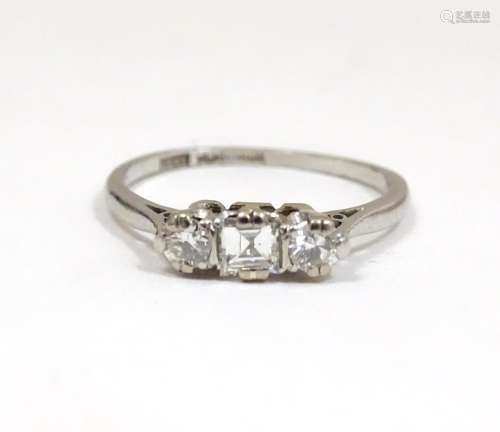 A platinum ring set with a central square cut diam…
