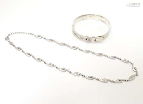 A silver bangle formed bracelet styled as a belt w…