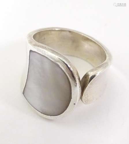 A silver ring with mother of pearl detail. Ring si…