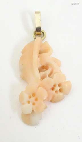 A carved coral coloured pendant with floral detail…