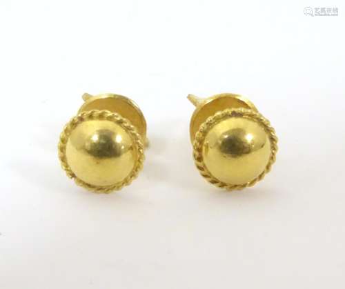 A pair of gold stud earrings. Marked 22k and with …