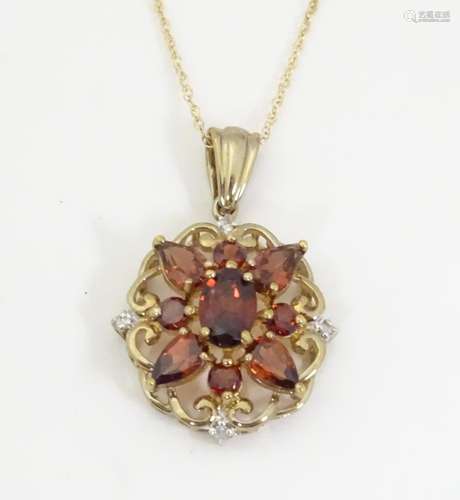 A 9ct gold pendant set with diamonds and red stone…