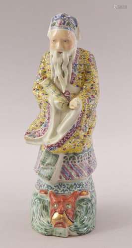 A CHINESE FAMILLE ROSE PORCELAIN FIGURE OF A SAGE, stood upo...