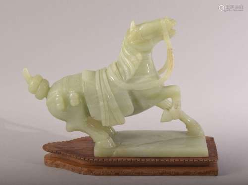 A CHINESE CARVED JADE MODEL OF A HORSE, with a wooden stand,...