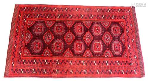 A PERSIAN TEKKE BOKHARA DESIGN RUG, red ground with lozenge ...
