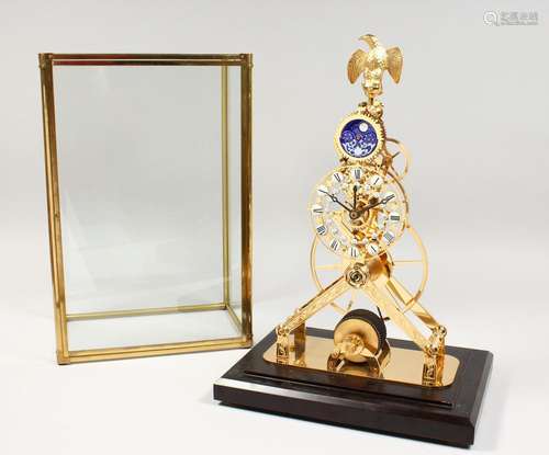 A BRASS SKELETON MOONPHASE CLOCK in a glass case. 17ins high...