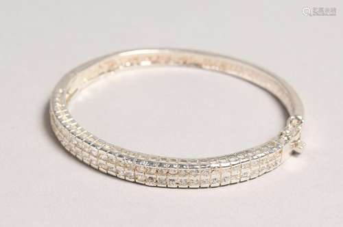 A SILVER CUBIC ZIRCONIA BANGLE.