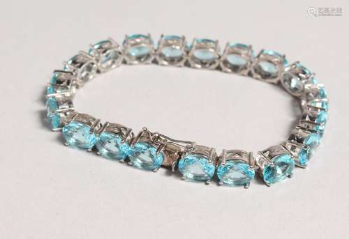 A SILVER BLUE TOPAZ SET LINE BRACELET.