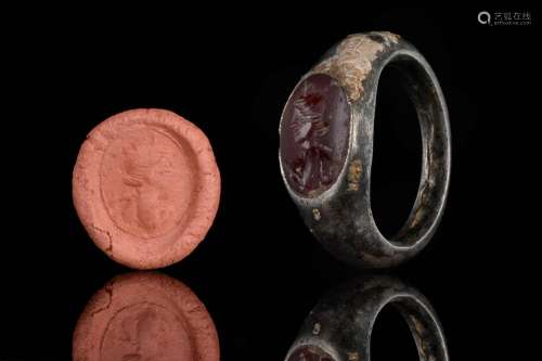 A ROMAN BRONZE RING WITH CARNELIAN INTAGLIO DEPICTING BUST O...