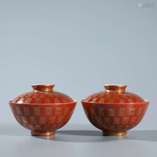 A pair of gold covered bowls with red background