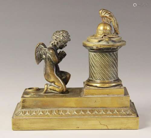 A brass desk inkwell, 19th century, designed as a cherub kne...