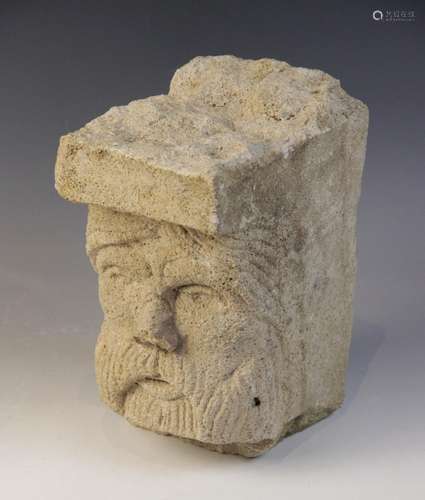 A carved stone head, distinctively carved with a bearded gen...