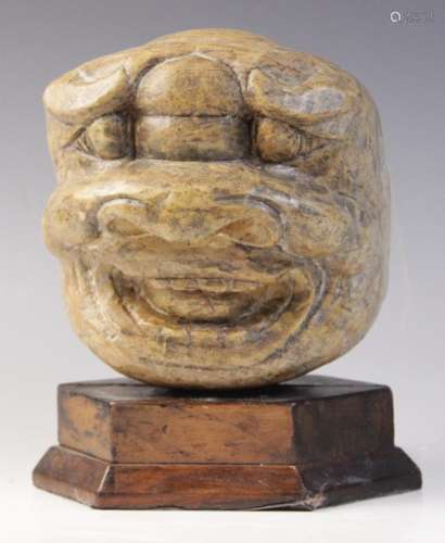 A carved stone sculpture of a grinning grotesque mask, 15.5c...