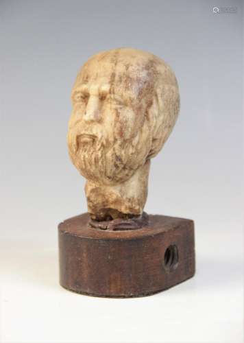 A carved marble male head, 9cm high, upon a later wooden bas...